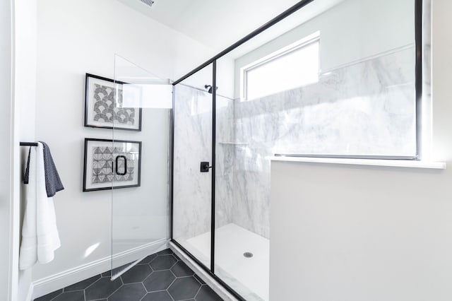 bathroom featuring tile patterned flooring, baseboards, and a marble finish shower