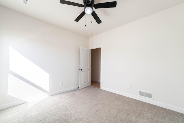 carpeted spare room featuring a ceiling fan, visible vents, and baseboards