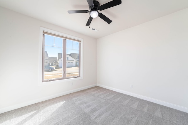 empty room featuring baseboards, ceiling fan, visible vents, and light colored carpet