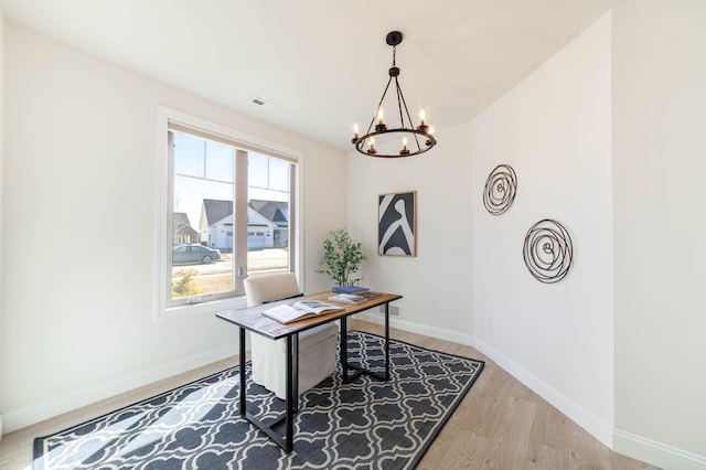 office featuring a notable chandelier, light wood-style flooring, visible vents, and baseboards