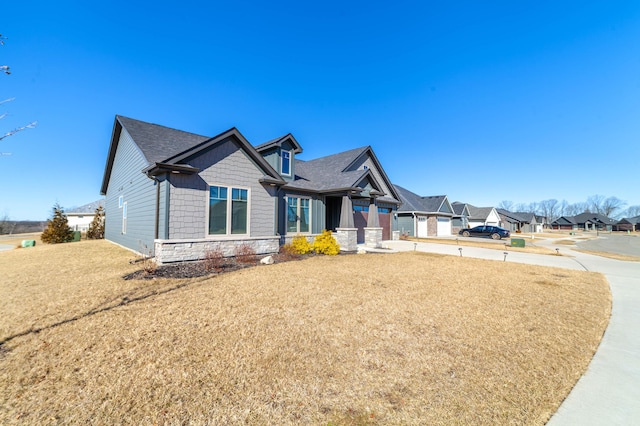 craftsman inspired home with stone siding, a residential view, and a front lawn