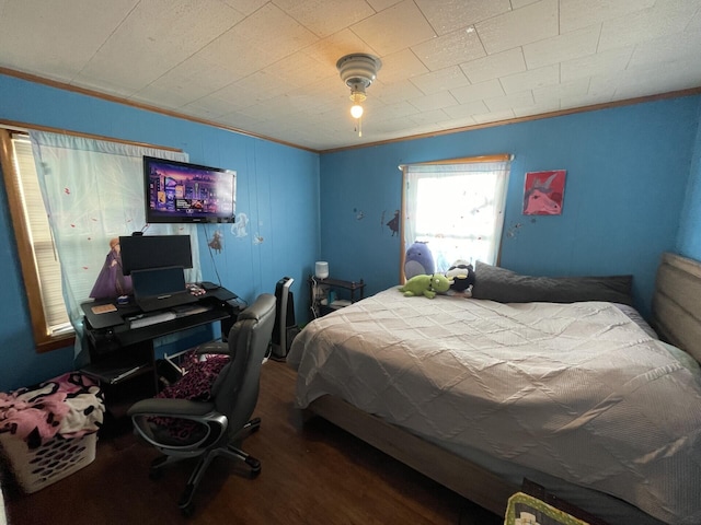 bedroom with crown molding and wood finished floors