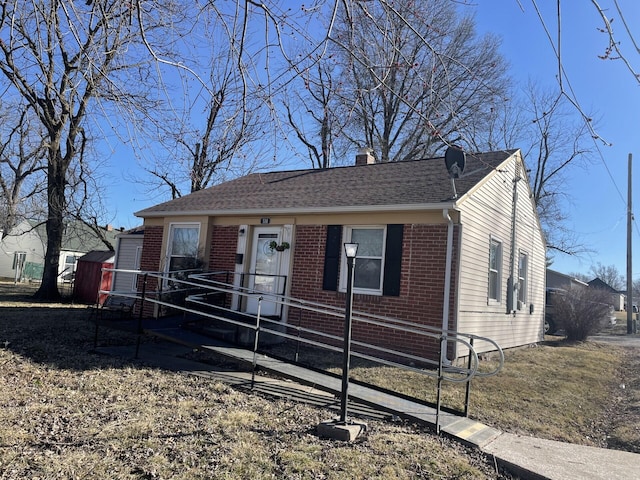 view of front facade with brick siding, a chimney, and roof with shingles