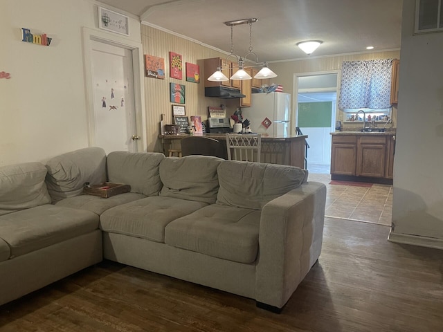 living area with visible vents, wood finished floors, and ornamental molding