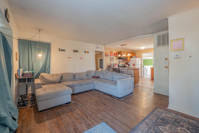 living room featuring baseboards, wood finished floors, visible vents, and a chandelier