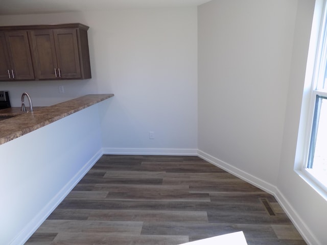 unfurnished dining area with visible vents, a sink, dark wood finished floors, and baseboards