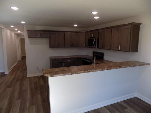 kitchen with a peninsula, electric range, baseboards, dark wood-style floors, and stainless steel microwave