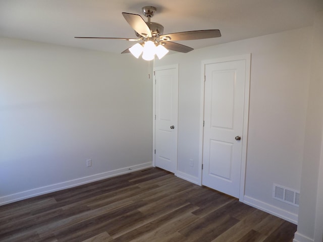 unfurnished bedroom featuring ceiling fan, dark wood-style flooring, visible vents, and baseboards