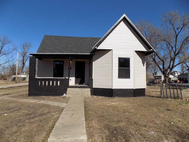 bungalow-style home featuring a porch, a shingled roof, and fence