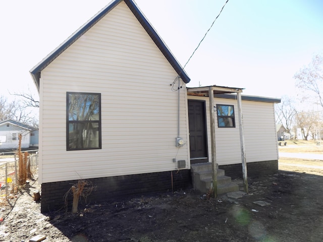 rear view of property featuring entry steps and fence