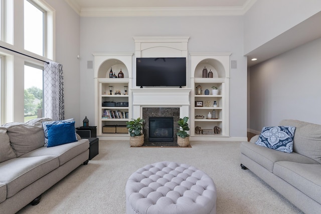 carpeted living area featuring ornamental molding, a premium fireplace, a towering ceiling, and built in features