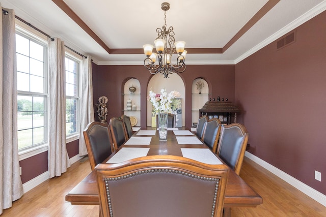 dining area with a tray ceiling, visible vents, light wood-style floors, a chandelier, and baseboards