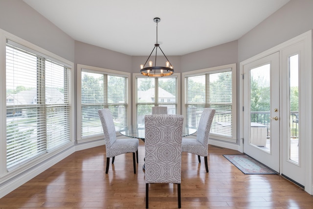 dining space with a chandelier, wood-type flooring, and a healthy amount of sunlight