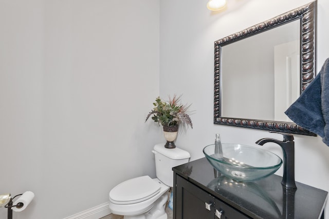 half bath featuring toilet, vanity, and baseboards