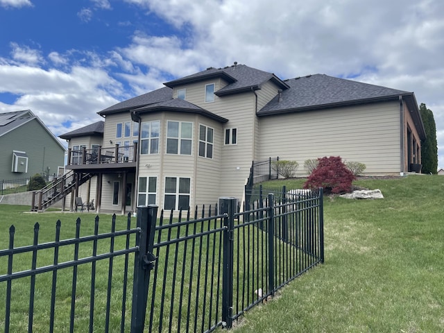 back of house featuring roof with shingles, a yard, a fenced backyard, a wooden deck, and stairs