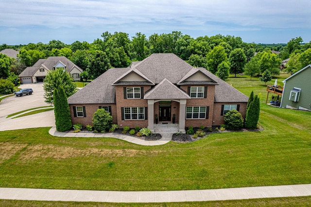 view of front of home with brick siding, a front lawn, and roof with shingles