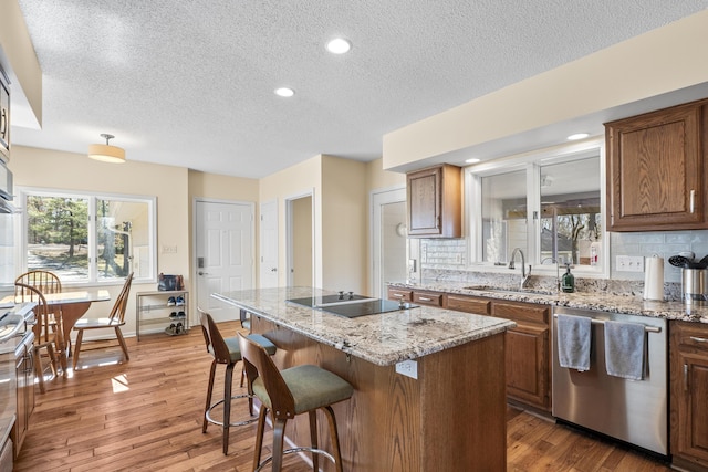 kitchen with hardwood / wood-style flooring, dishwasher, a sink, and black electric cooktop