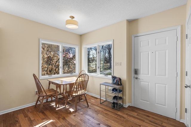 dining area featuring a textured ceiling, baseboards, and hardwood / wood-style flooring