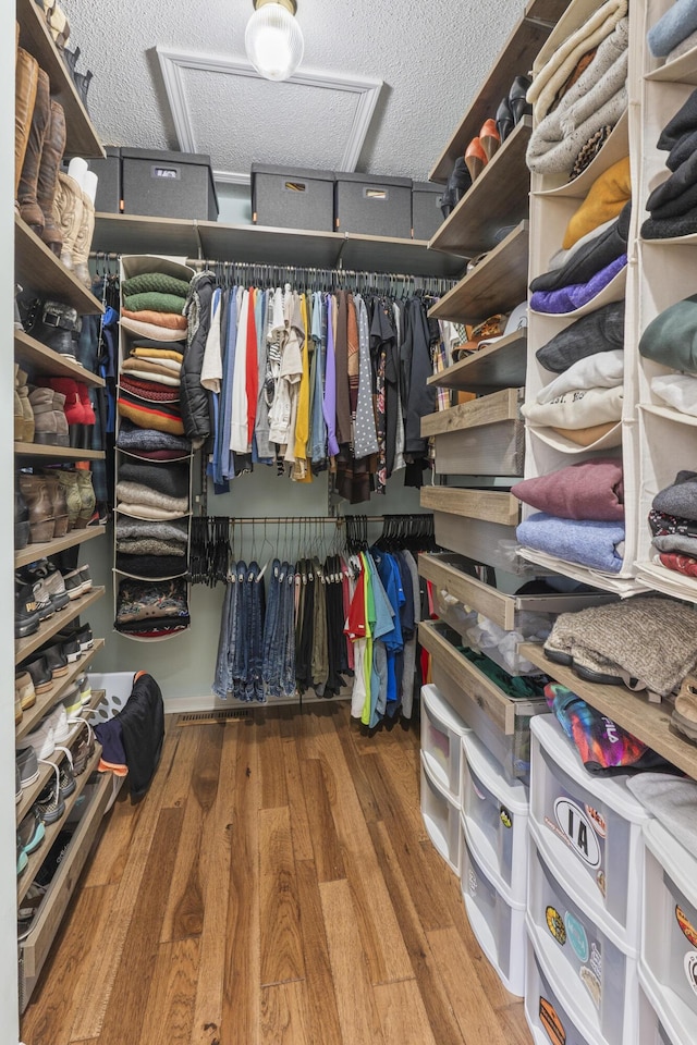 walk in closet featuring attic access and wood finished floors