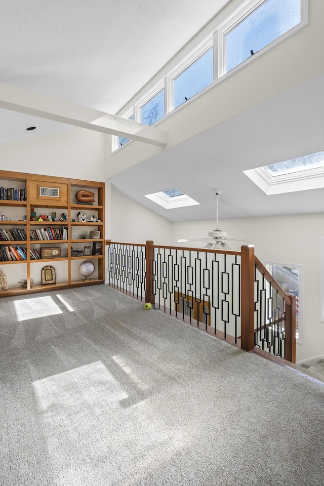 interior space featuring a skylight, carpet, high vaulted ceiling, and a ceiling fan