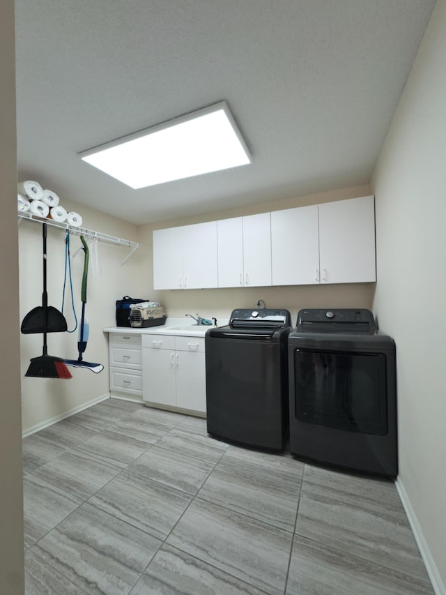 washroom featuring cabinet space, baseboards, a sink, and washing machine and clothes dryer