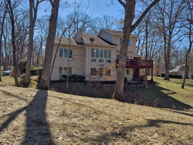 rear view of property with a yard, a chimney, and a wooden deck