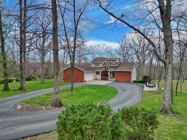 view of front facade featuring brick siding, driveway, a front yard, and a garage