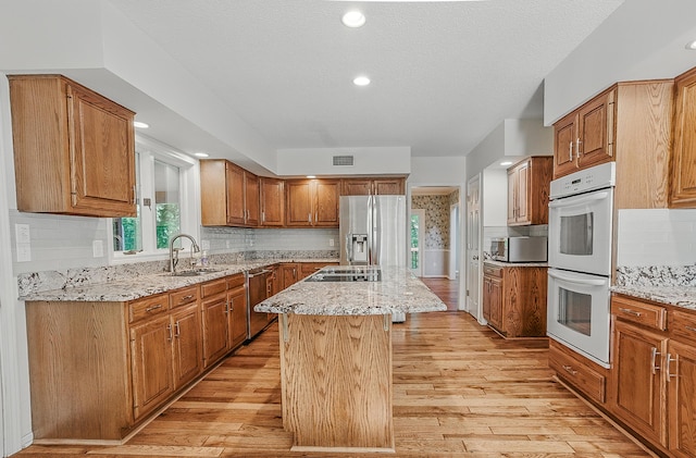 3700 S Joan Ct, Columbia, MO 65201 - kitchen featuring stainless steel appliances, a kitchen island, light stone counters, light wood finished floors, and a textured ceiling
