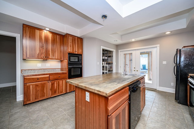 kitchen with a sink, baseboards, black appliances, a tray ceiling, and brown cabinetry