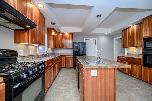 kitchen with black appliances, under cabinet range hood, a raised ceiling, and a sink