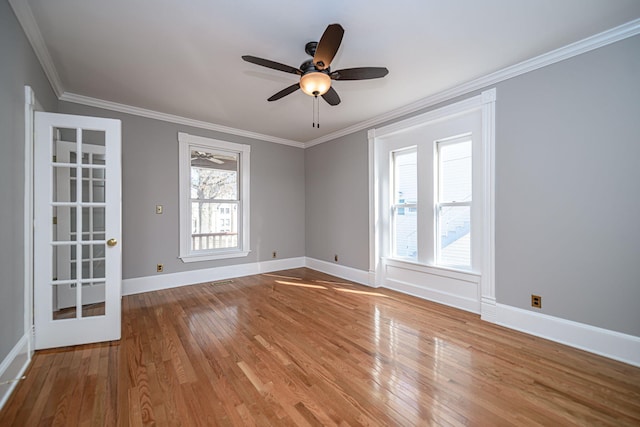 empty room with a ceiling fan, baseboards, crown molding, and wood finished floors