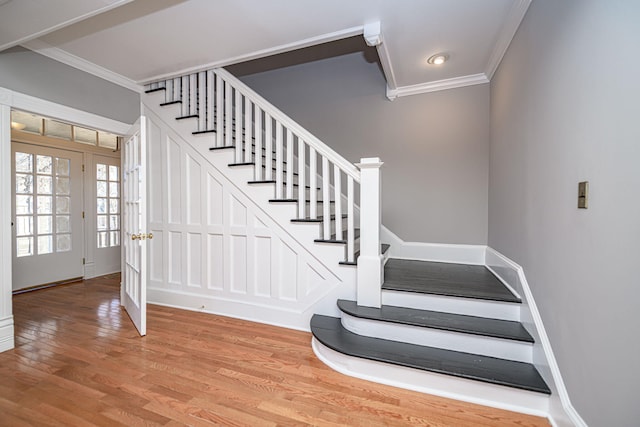 stairway featuring ornamental molding, baseboards, and wood finished floors