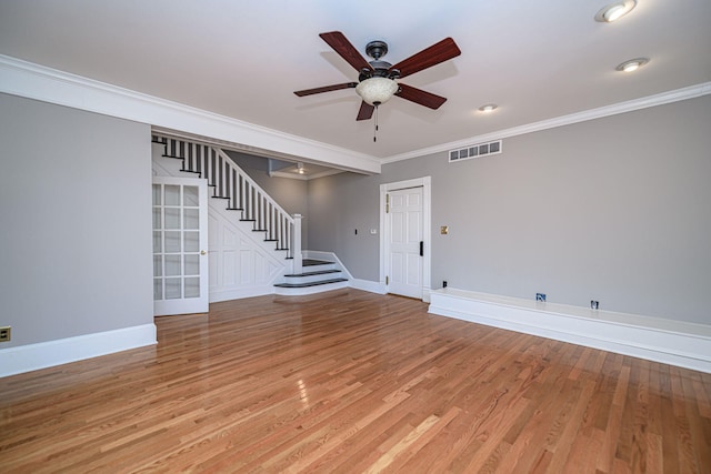 unfurnished room with visible vents, baseboards, ornamental molding, stairway, and light wood finished floors