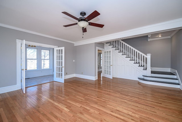 unfurnished living room with light wood-style flooring, baseboards, stairs, french doors, and crown molding