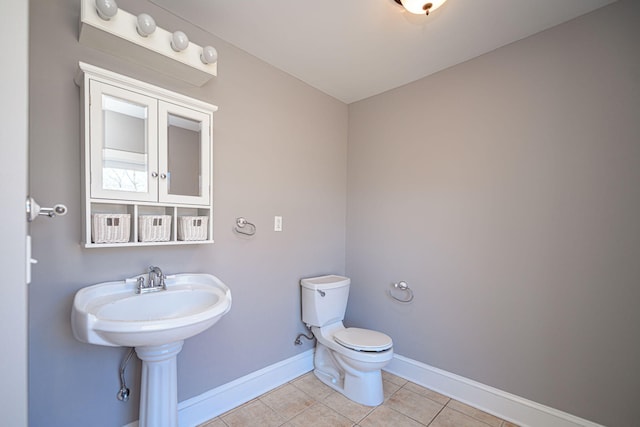 half bath featuring toilet, baseboards, and tile patterned floors