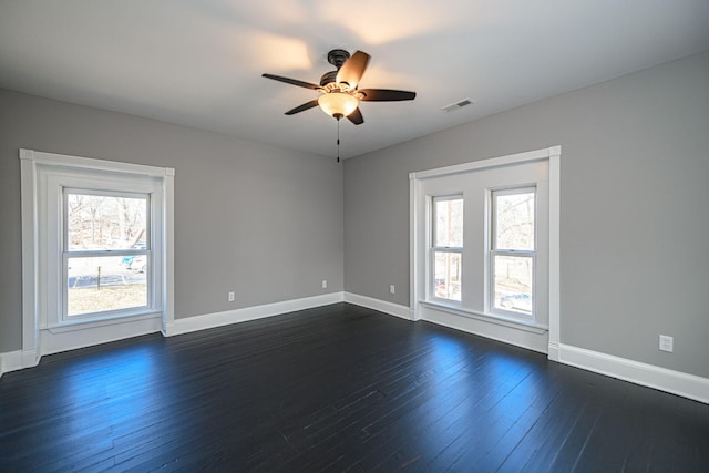 empty room with a healthy amount of sunlight, visible vents, and dark wood finished floors