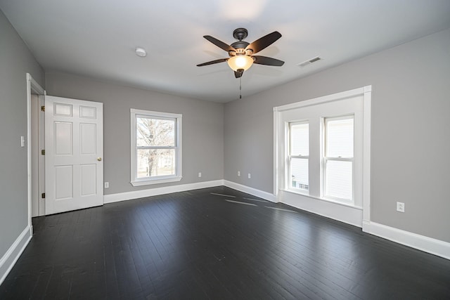 empty room featuring a ceiling fan, dark wood-style flooring, visible vents, and baseboards