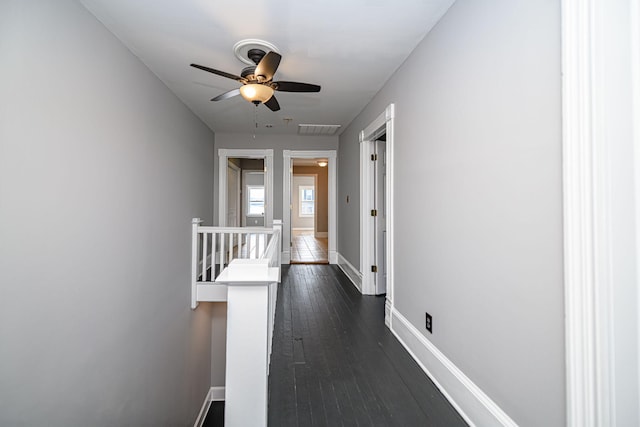 hallway with visible vents, baseboards, dark wood-type flooring, and an upstairs landing