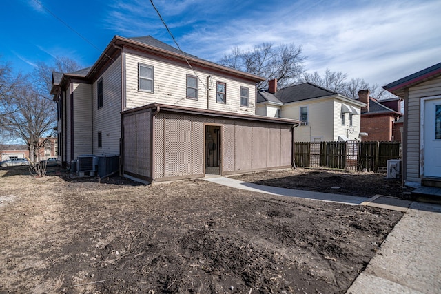 back of property with central AC unit and fence