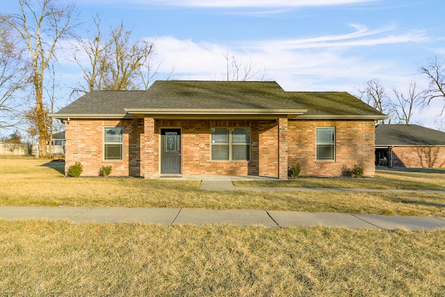 view of front of home featuring brick siding, roof with shingles, and a front yard