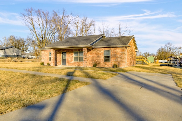 view of front of property with roof with shingles, brick siding, and a front lawn