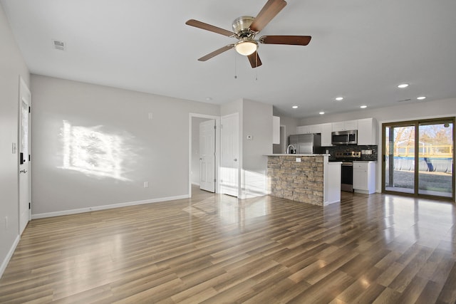 unfurnished living room featuring recessed lighting, visible vents, ceiling fan, wood finished floors, and baseboards