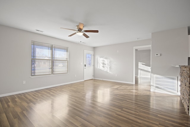 unfurnished living room featuring wood finished floors, visible vents, and baseboards