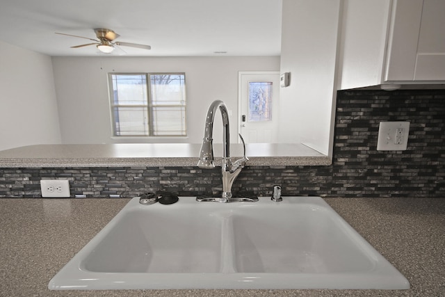 interior details with tasteful backsplash, white cabinetry, a sink, and ceiling fan