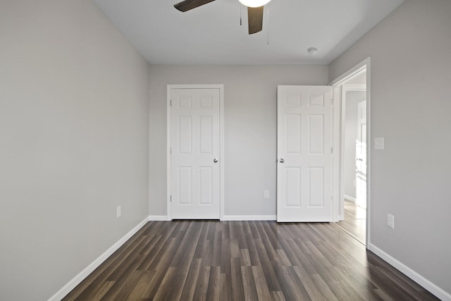 unfurnished bedroom with ceiling fan, dark wood-type flooring, and baseboards