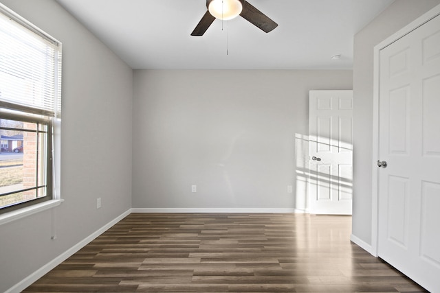 unfurnished room featuring dark wood-style floors, a ceiling fan, and baseboards