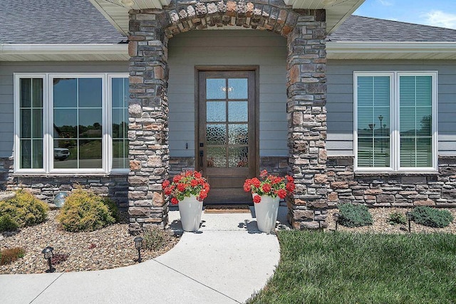 property entrance featuring stone siding and a shingled roof