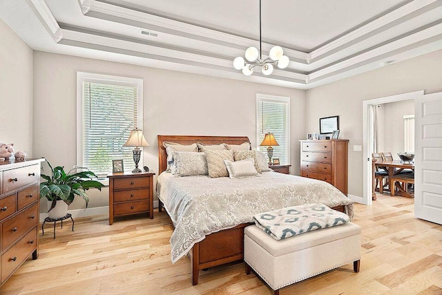 bedroom featuring a tray ceiling, multiple windows, light wood-style flooring, and crown molding