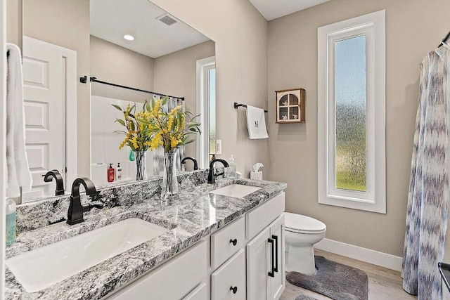 full bath featuring toilet, visible vents, a sink, and baseboards