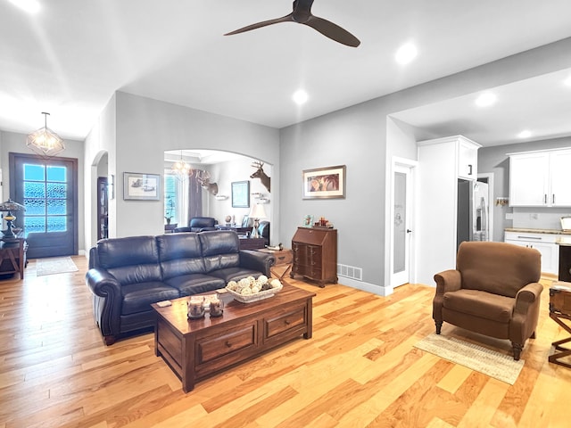 living area featuring arched walkways, recessed lighting, visible vents, light wood-style floors, and baseboards